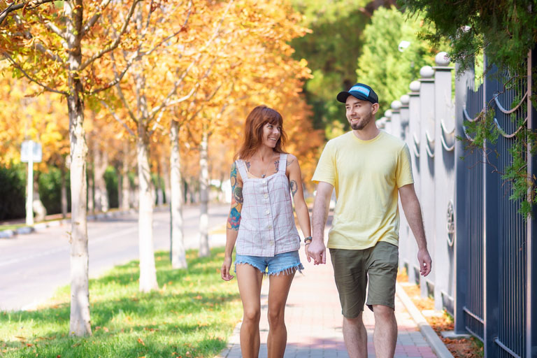 Young caucasian couple walking down the street. Happy caucasian woman with tattoos and bearded smiling man spend time together. The concept of relationship psychology.