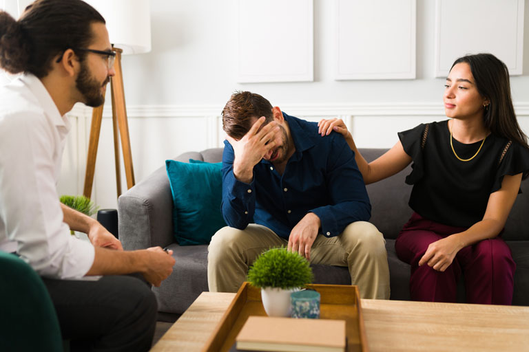 man crying during couples therapy with his partner. Woman and her husband at the therapist