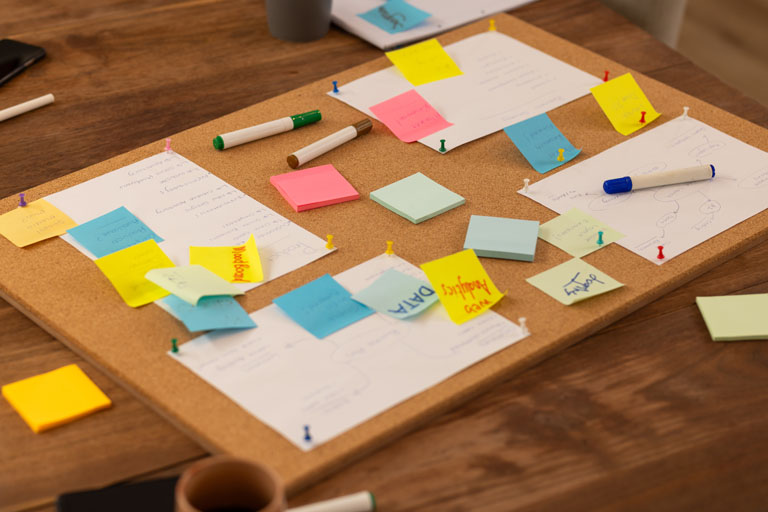 Brainstorming ideas, using sticky notes and markers on corkboard in office, start up business. teamwork, creativity, collaboration, organization, planning, workspace