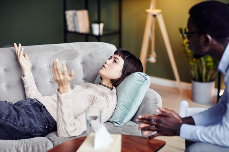 Young woman sharing struggles during private therapy session with psychologist